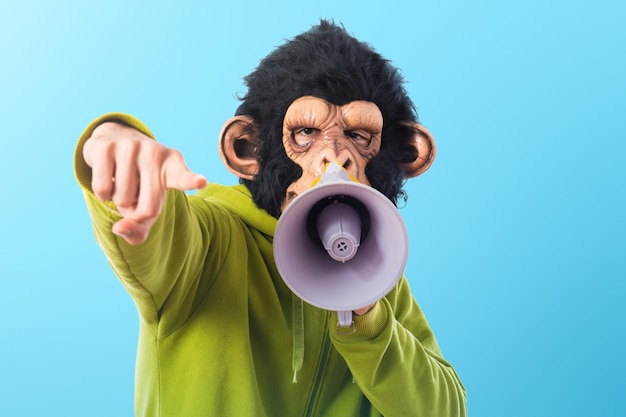 Mono hombre gritando por megáfono sobre fondo de colores