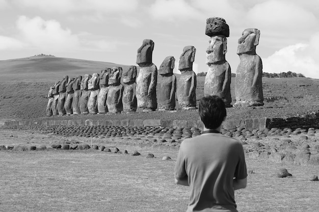 Monochromes Bild massiver Moai-Statuen der zeremoniellen Plattform Ahu Tongariki mit Besucher im Vordergrund, Osterinsel, Chile