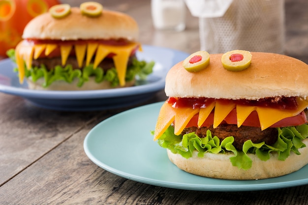 Monstruos de hamburguesa de Halloween en mesa de madera