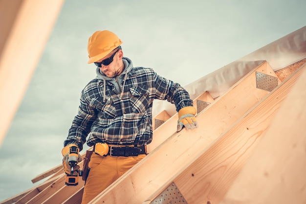 Montación del marco del esqueleto del techo de una casa de madera por un trabajador profesional de la construcción