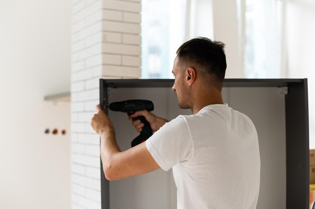 Montagem de novos móveis de madeira à mão no quarto. Homem montando móveis novos.