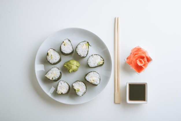 Montagem de rolos de sushi vegetarianos de abacate e pepino com gengibre wasabi e molho de soja