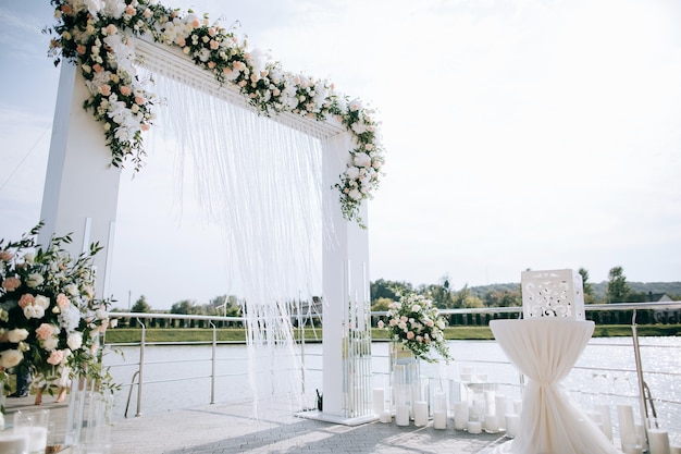 Montaje de boda, recepción de boda al aire libre con arco en la orilla del lago