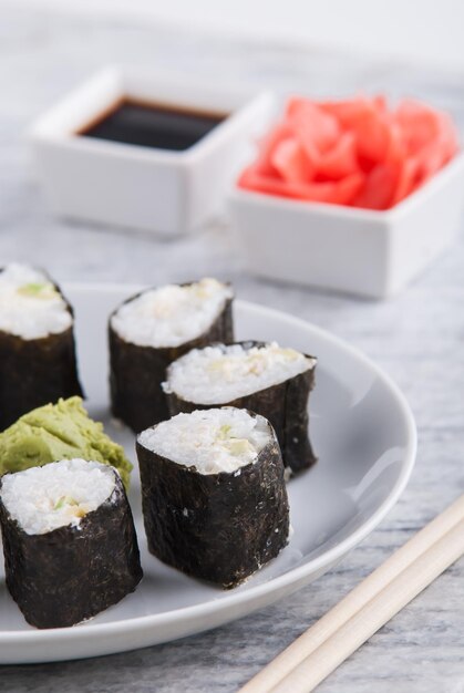 Montaje de rollos de sushi vegetariano de aguacate y pepino con wasabi de jengibre y salsa de soja