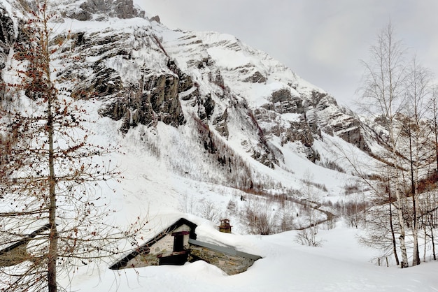 Montaña alpina en la nieve con un chalet enterrado en la nieve