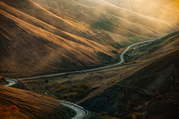 Montaña con camino y bosque al atardecer.