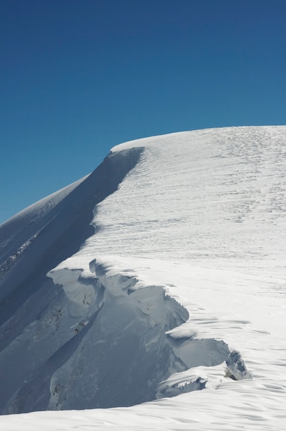 Montaña de invierno con tapas de nieve en voladizo en el cielo azul