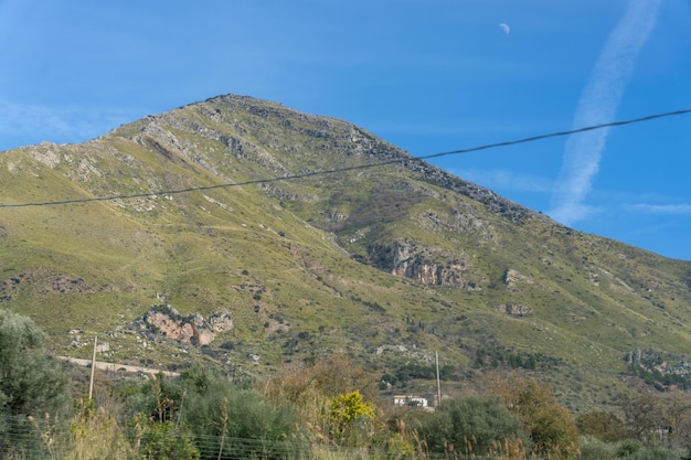 Una montaña con una ladera verde y un cielo azul claro