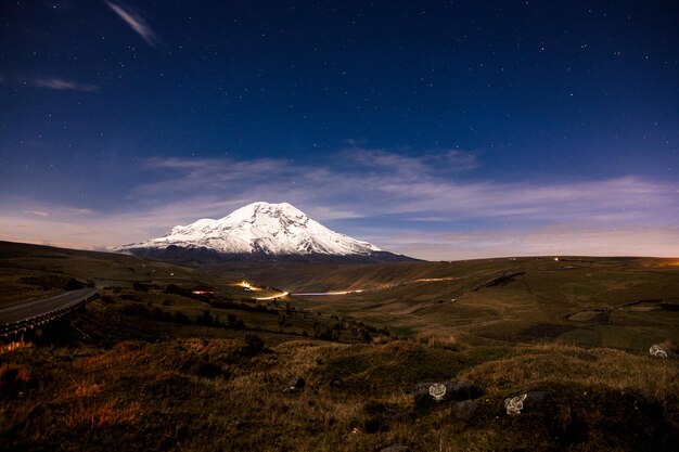 una montaña se muestra con un cielo que tiene algunas nubes en él