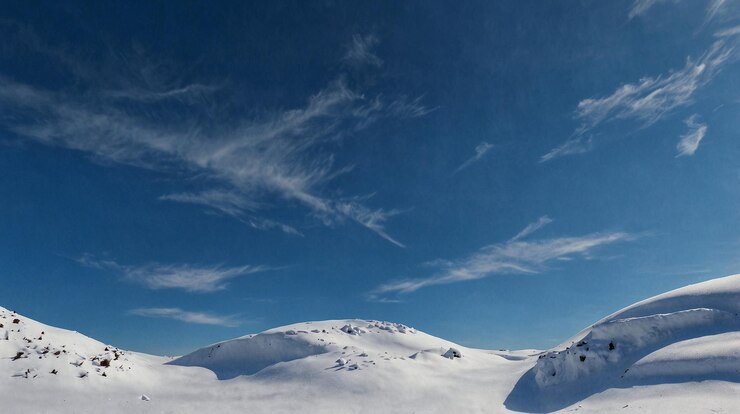 una montaña nevada con un cielo azul y algunas nubes