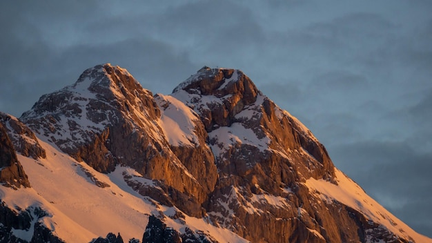 una montaña con nieve y un cielo nublado en el fondo