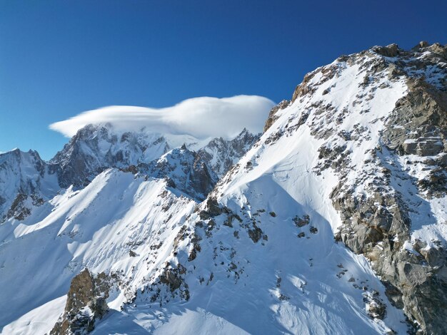 Una montaña con nieve y una nube en la cima