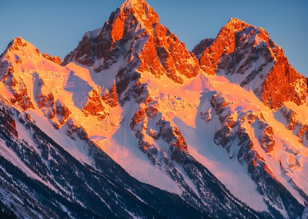 Una montaña con nieve y el sol brillando sobre ella.