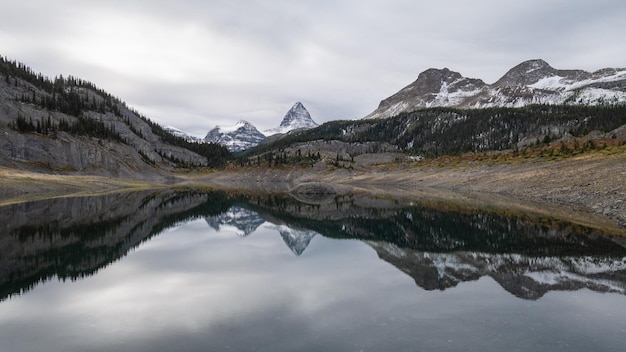 Montaña prominente que se refleja en el lago alpino durante el día nublado pano mt assiniboine pp canadá
