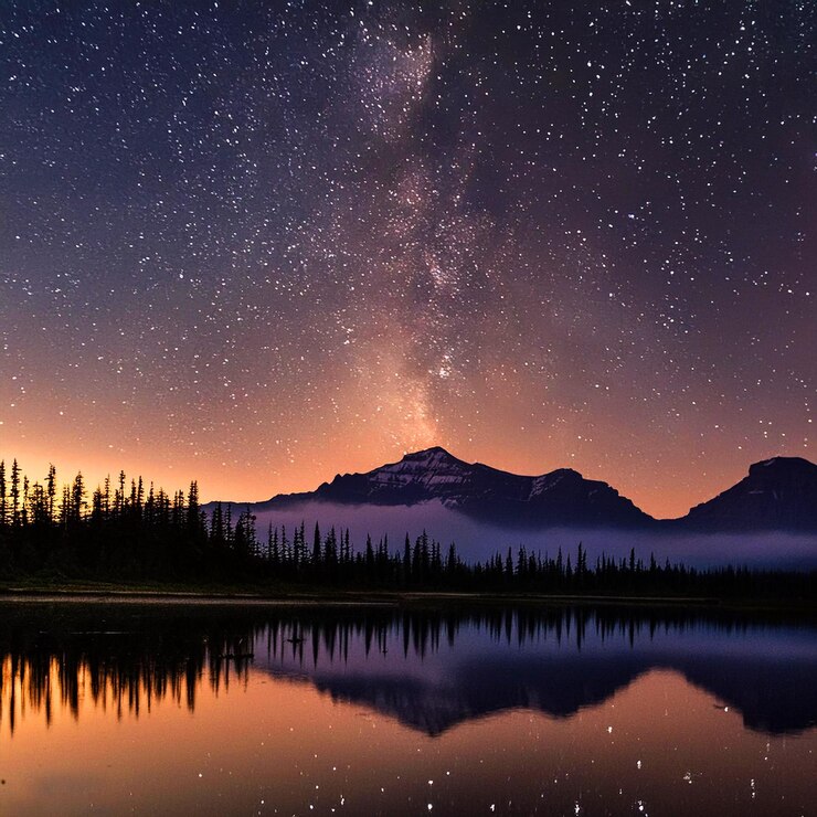una montaña se refleja en un lago con una montaña en el fondo