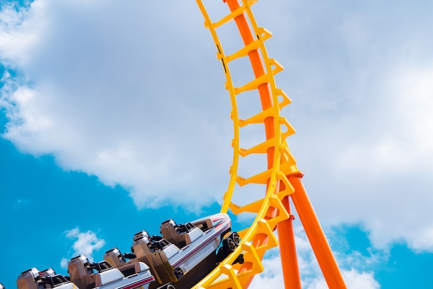 Montaña rusa en lo alto del cielo de verano en el parque temático más emocionada, divertida y alegre máquina de juego