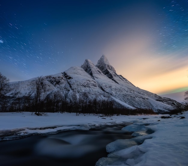 Montañas y cielo estrellado en movimiento Islas Senja Noruega Paisaje invernal con cielo nocturno Río y montañas en invierno Imagen de viaje de Noruega