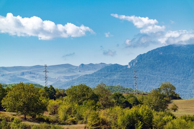 Montañas cubiertas de un denso bosque verde, torres de transmisión de energía