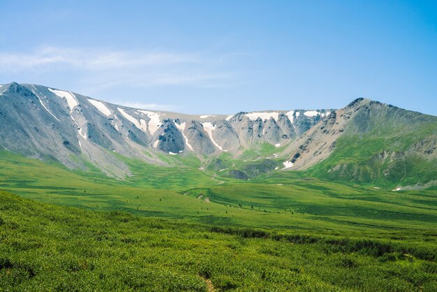 Montañas gigantes sobre el valle verde en día soleado.