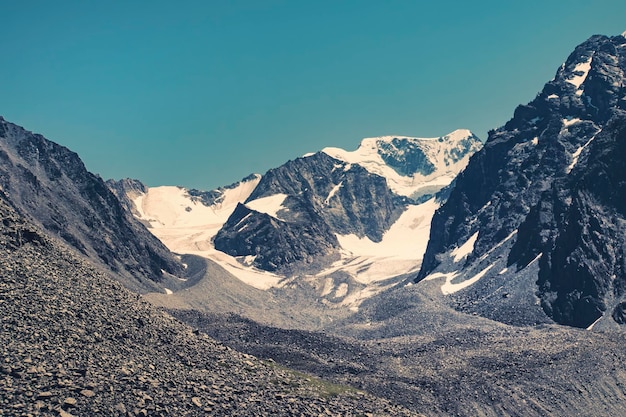 Montañas con gorras de nieve en un teñido oscuro de las montañas de Altai, Siberia, Rusia