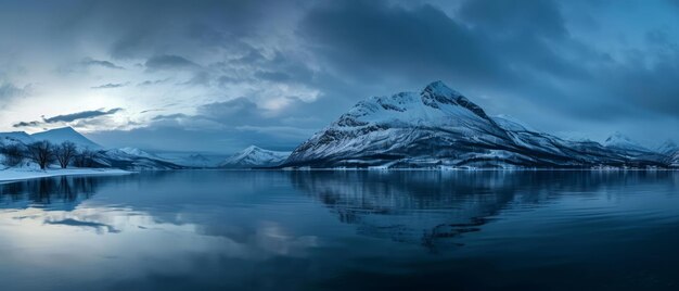 Montañas nevadas en un día de invierno cerca del lago bajo un cielo oscuro al amanecer