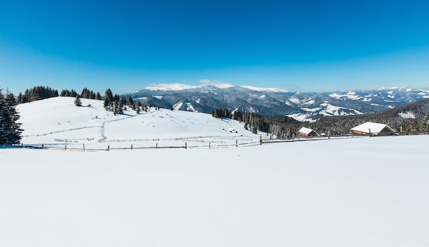 Montañas nevadas de invierno y granja solitaria