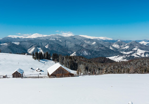 Montañas nevadas de invierno y granja solitaria