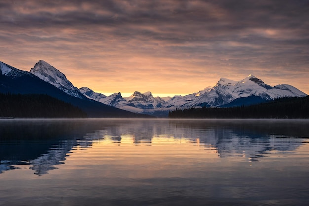 Montañas rocosas canadienses con reflejo brumoso en el lago Maligne y cielo colorido por la mañana en el parque nacional Jasper, Canadá