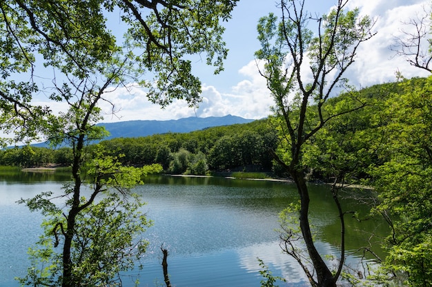 Las montañas rodean el lago de montaña. La superficie del lago refleja la luz del sol. Paisaje