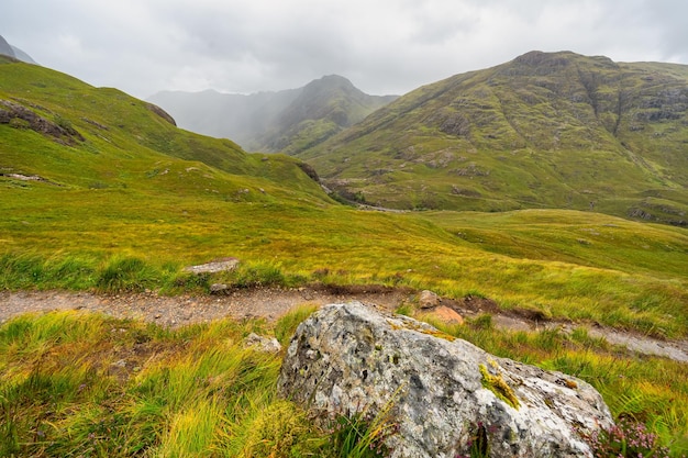 Montañas verdes cubiertas de niebla y rutas de senderismo en el valle de Glencoe Escocia