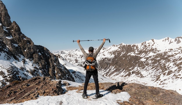Montañero desde atrás observando el paisaje nevado con los brazos levantados
