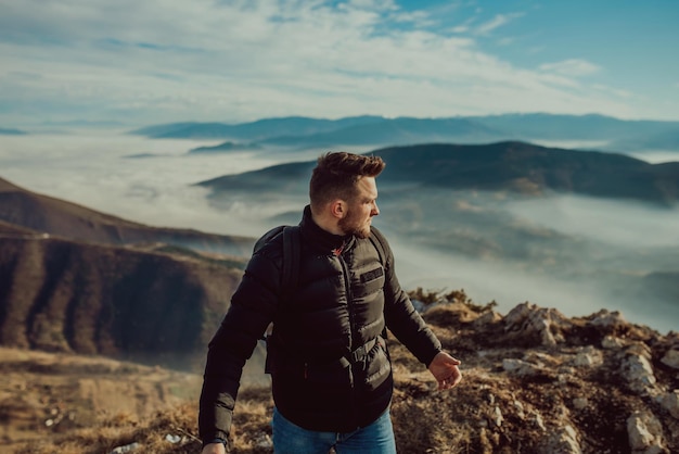 Un montañero con chaqueta y mochila en la cima de la montaña