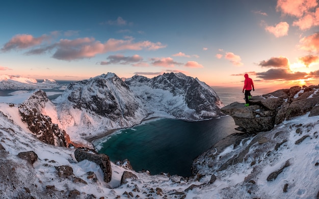 Montañero hombre de pie en la roca de la montaña pico al atardecer