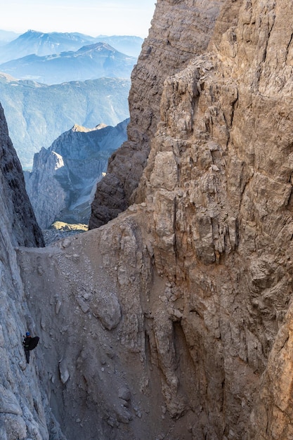 Montañero masculino en una vía ferrata en un paisaje impresionante de las montañas Dolomitas en Italia