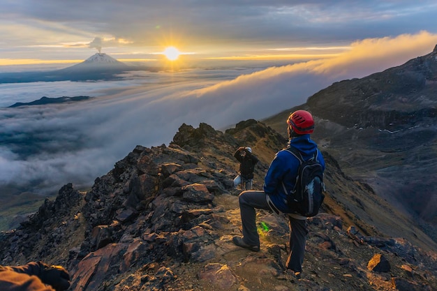 Montañero en el volcán ilinzia norte al amanecer al fondo el volcán cotopaxi