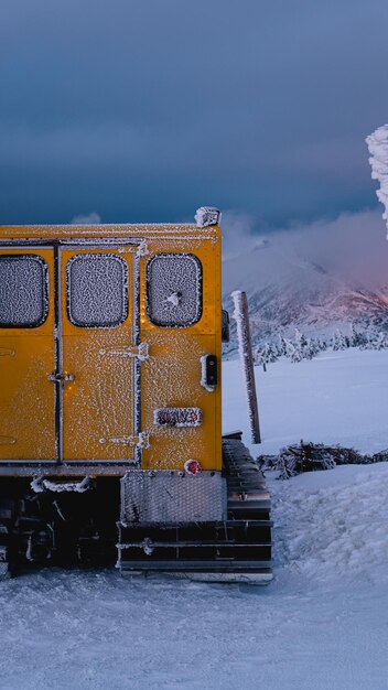 Montanha atmosférica coberta de neve com nuvens negras iluminadas pelo papel de parede vertical do sol poente para smartphone