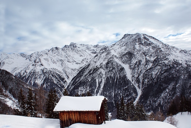 Montanha com neve e casa de madeira