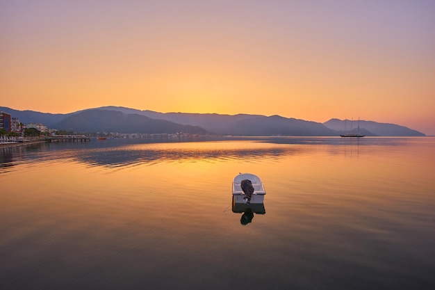 Montanha e barco a motor solitário refletiu o nascer do sol em um mar calmo marmaris