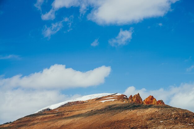 Montanha linda e ensolarada com penhascos marrom-laranja-avermelhados no topo sob o céu azul