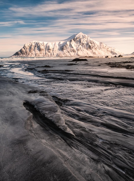 Montanha nevada na areia listrada no litoral na praia de Skagsanden