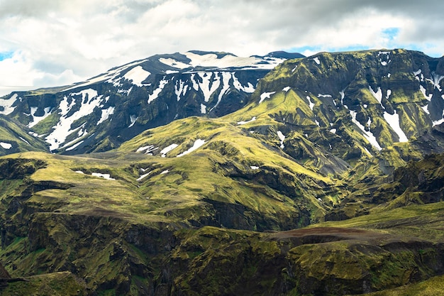 Montanha verde com textura áspera de musgo e coberto de neve nas terras altas islandesas na Islândia