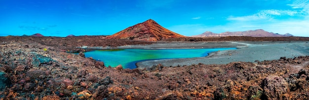 Montanha vermelha e poça verde perto da costa do mar nas praias das Ilhas Canárias, Lanzarote.Spain.