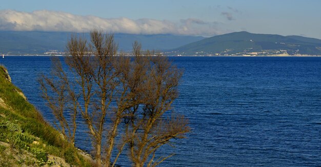 Montanhas altas do céu azul cobertas de nuvens ao pé da costa rochosa do mar sem fim Mar Negro Cabo Dolfin Novorossiysk Rússia