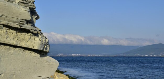 Montanhas altas do céu azul cobertas de nuvens ao pé da costa rochosa do mar sem fim Mar Negro Novorossiysk Rússia