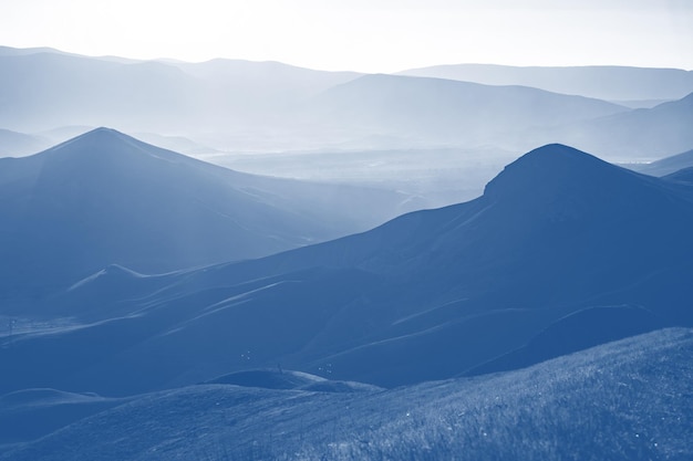 Montanhas baixas em névoa colorida em tons de cor azul clássico na moda 2020