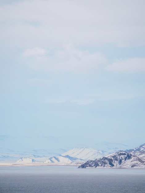 Foto montanhas cobertas de neve à distância e mar frio