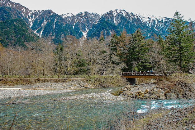 Montanhas cobertas de neve ao fundo e lago claro na cena de inverno em Kamikochi, Japão