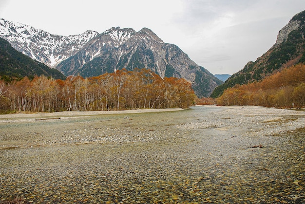 Montanhas cobertas de neve ao fundo e lago claro na cena de inverno em Kamikochi, Japão