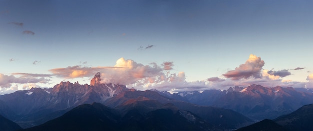 Montanhas cobertas de neve fantásticas nas belas nuvens cumulus