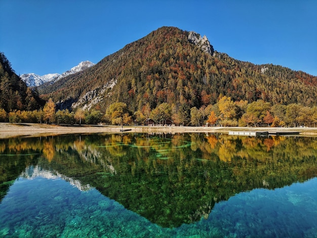 Montanhas dos Alpes do outono na luz do dia refletida nas águas do lago verde Jasna, Kranjska Gora. Eslovênia